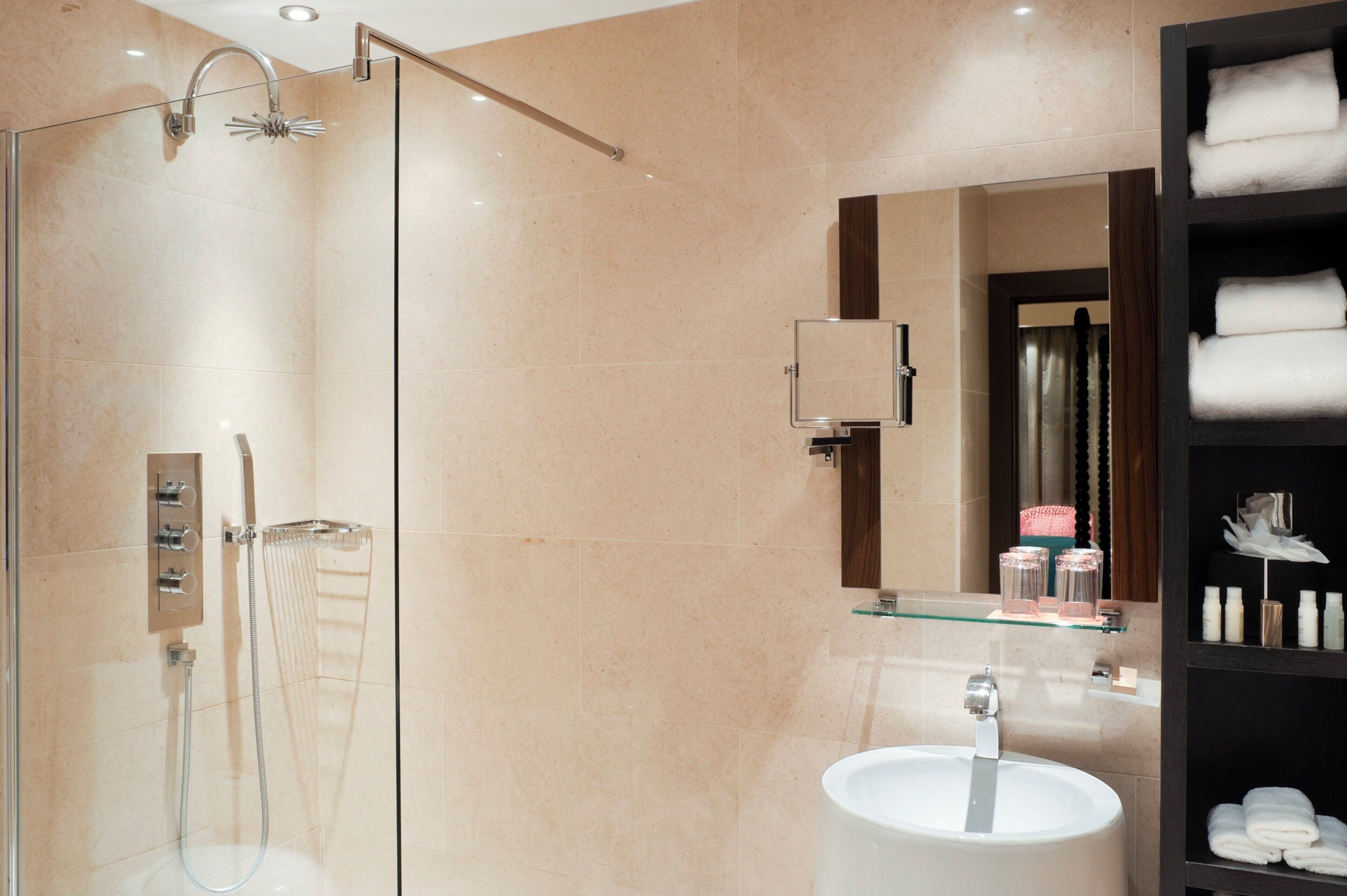 A modern bathroom with a glass-enclosed shower, a white sink, and a mirror above it.