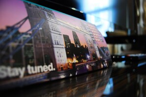 Revista o folleto con un paisaje urbano y el texto 'Stay tuned'.