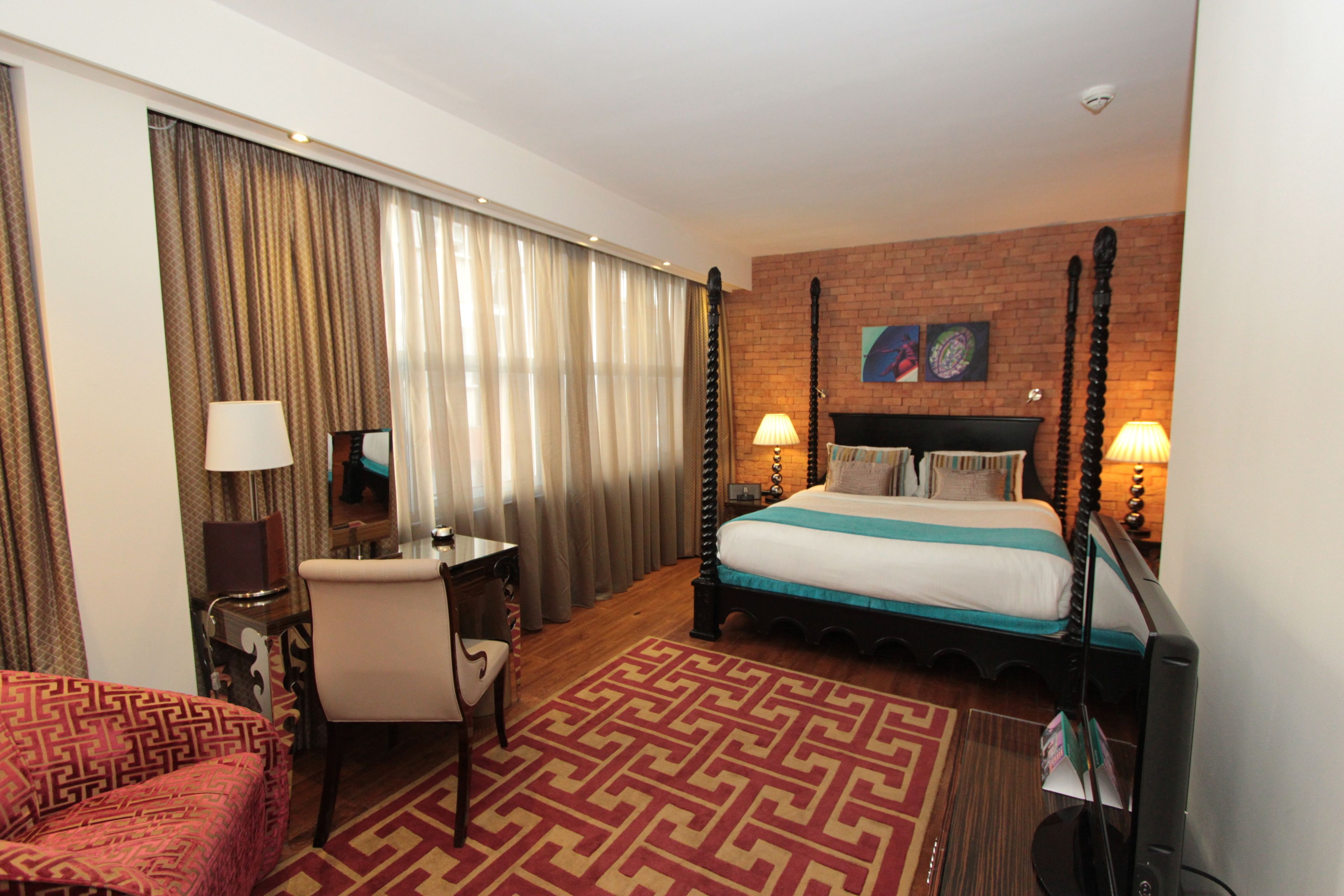 Una habitación de hotel con una cama grande, un escritorio, una silla y un televisor.