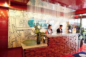 Un comptoir d’accueil agrémenté d’un mur décoratif sur lequel figure un grand panneau, un vase rempli de fleurs et un motif mural en briques.