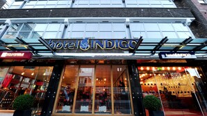 L’extérieur de l’hôtel Indigo se distingue par ses grandes fenêtres en verre et sa façade moderne.