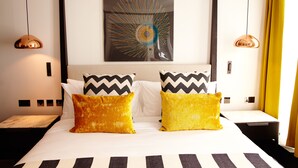 Une chambre d’hôtel avec un lit, deux oreillers, une œuvre d’art murale et une table de chevet.