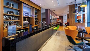 A bar area with shelves of liquor bottles, a counter with a menu, and orange chairs. - Park Inn by Radisson Aberdeen (Aberdeen)