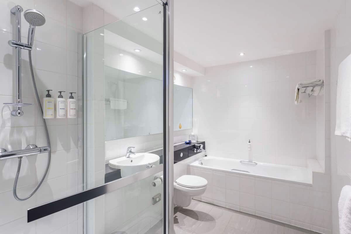 Un baño moderno con ducha envuelta en vidrio, un lavamanos blanco, un inodoro y una bañera.