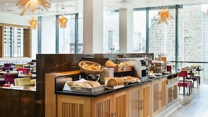A breakfast buffet area with a variety of bread and pastries, a coffee machine, and seating arrangements. - Park Inn by Radisson Aberdeen (Aberdeen)