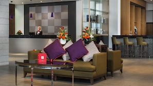A modern lobby with a reception desk, seating area with a sofa and armchairs, a bar area with stools, and decorative flower arrangements. - Park Inn by Radisson Aberdeen (Aberdeen)