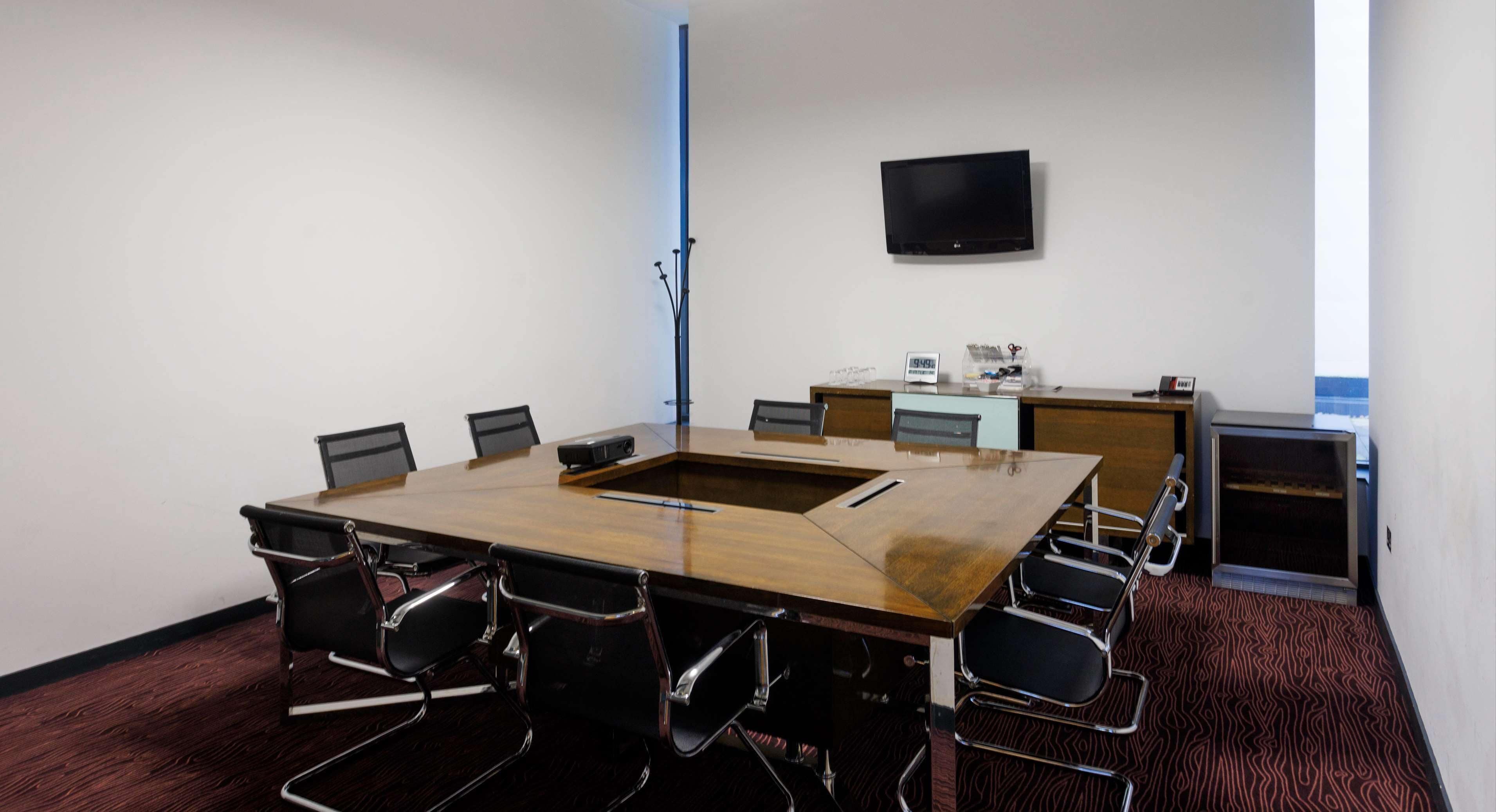 Ett konferensrum med ett stort bord, stolar, en platt-TV och ett litet pentry.