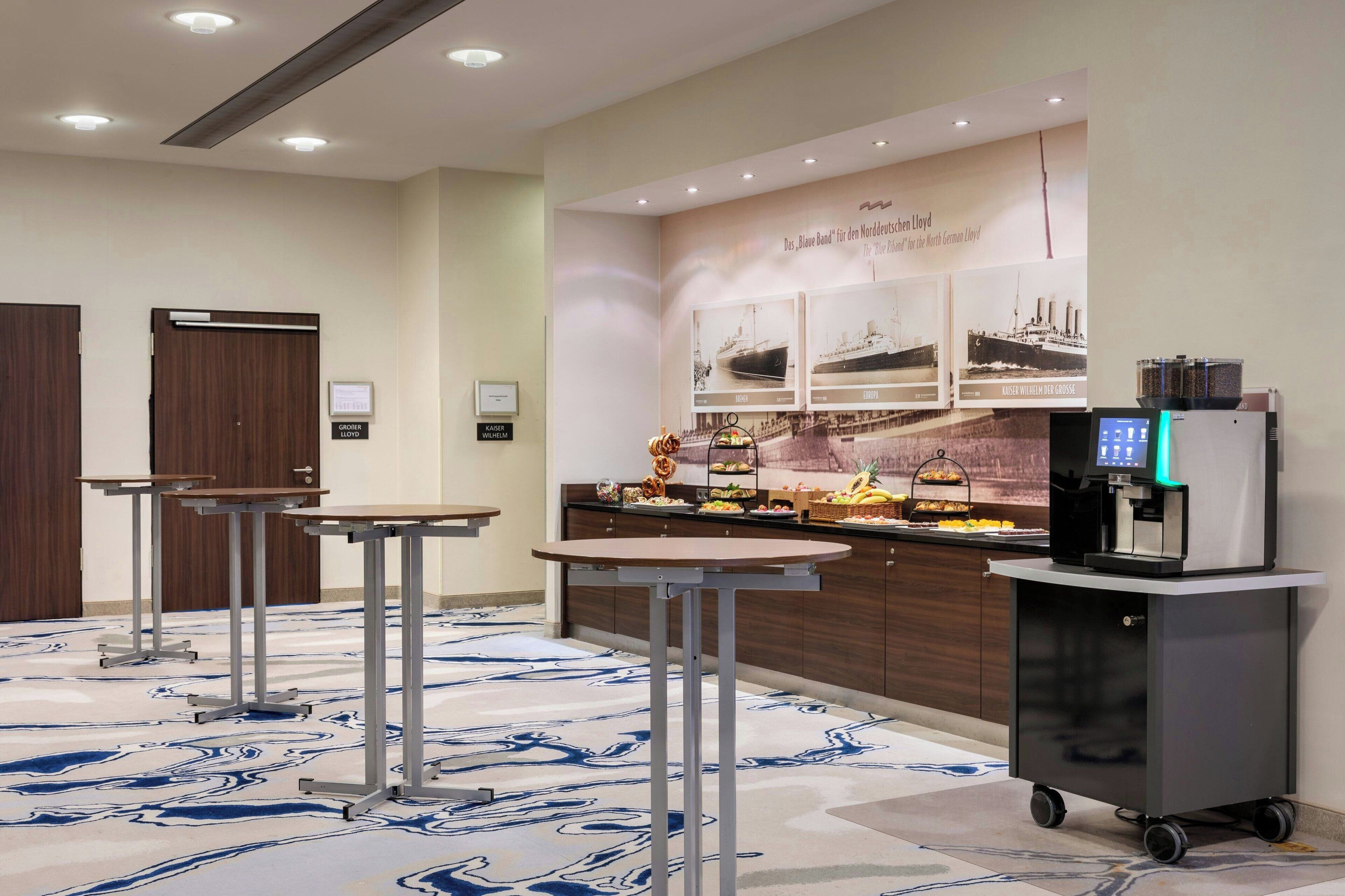 A hotel lobby with a reception desk, a coffee machine, and a buffet area.