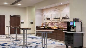 A hotel lobby with a reception desk, a coffee machine, and a buffet area.