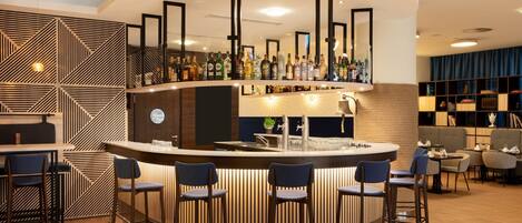 A modern bar area with a curved counter, bar stools, and a variety of bottles.