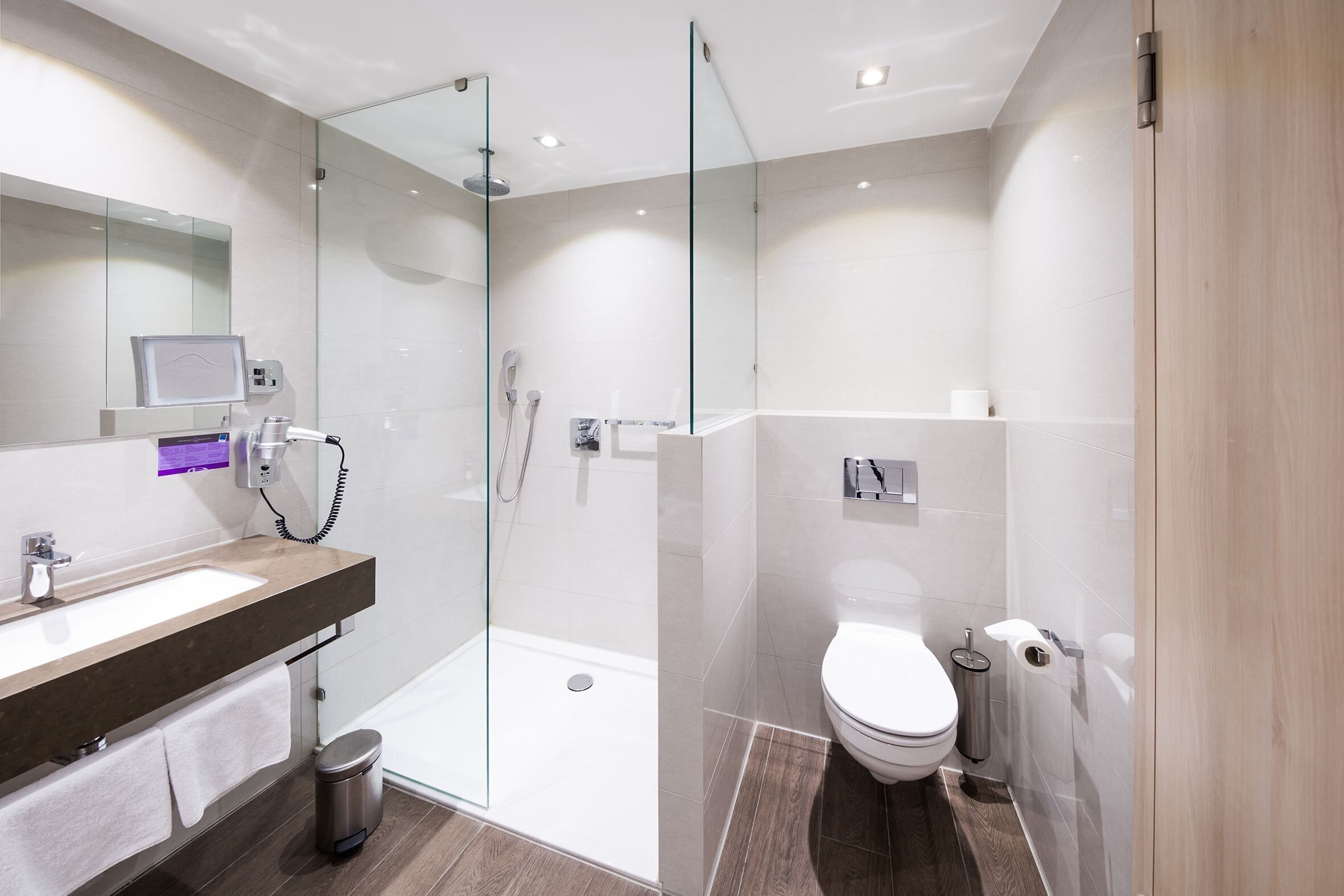 A modern bathroom with a glass-enclosed shower, a white sink, and a toilet.