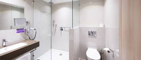 A modern bathroom with a glass-enclosed shower, a white sink, and a toilet.