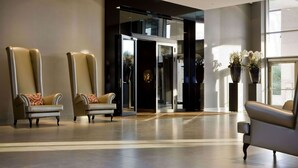 Un vestíbulo con dos sillones de cuero, una puerta de cristal y una planta en maceta.
