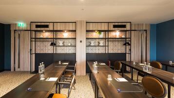 A conference room with long tables, chairs, and shelves with decorative items.