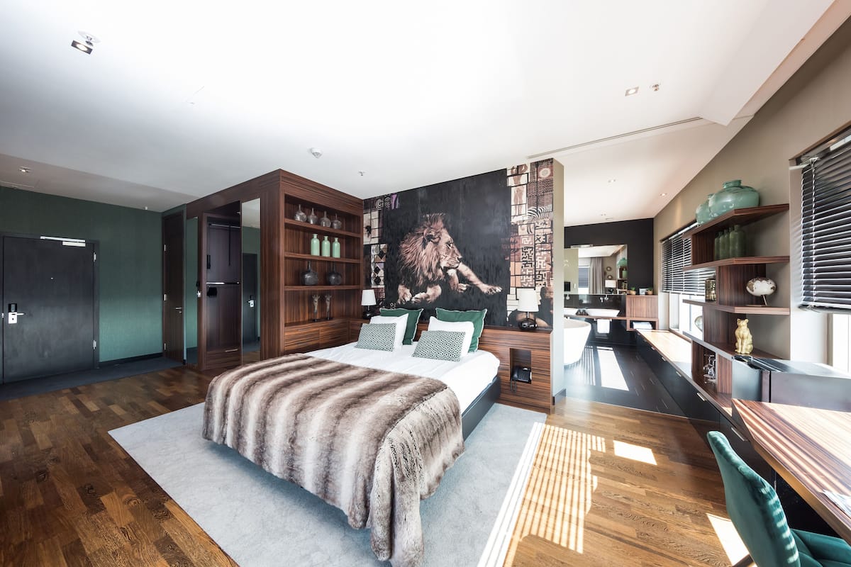 Une chambre moderne avec un grand lit, des étagères en bois et une fresque représentant un lion.