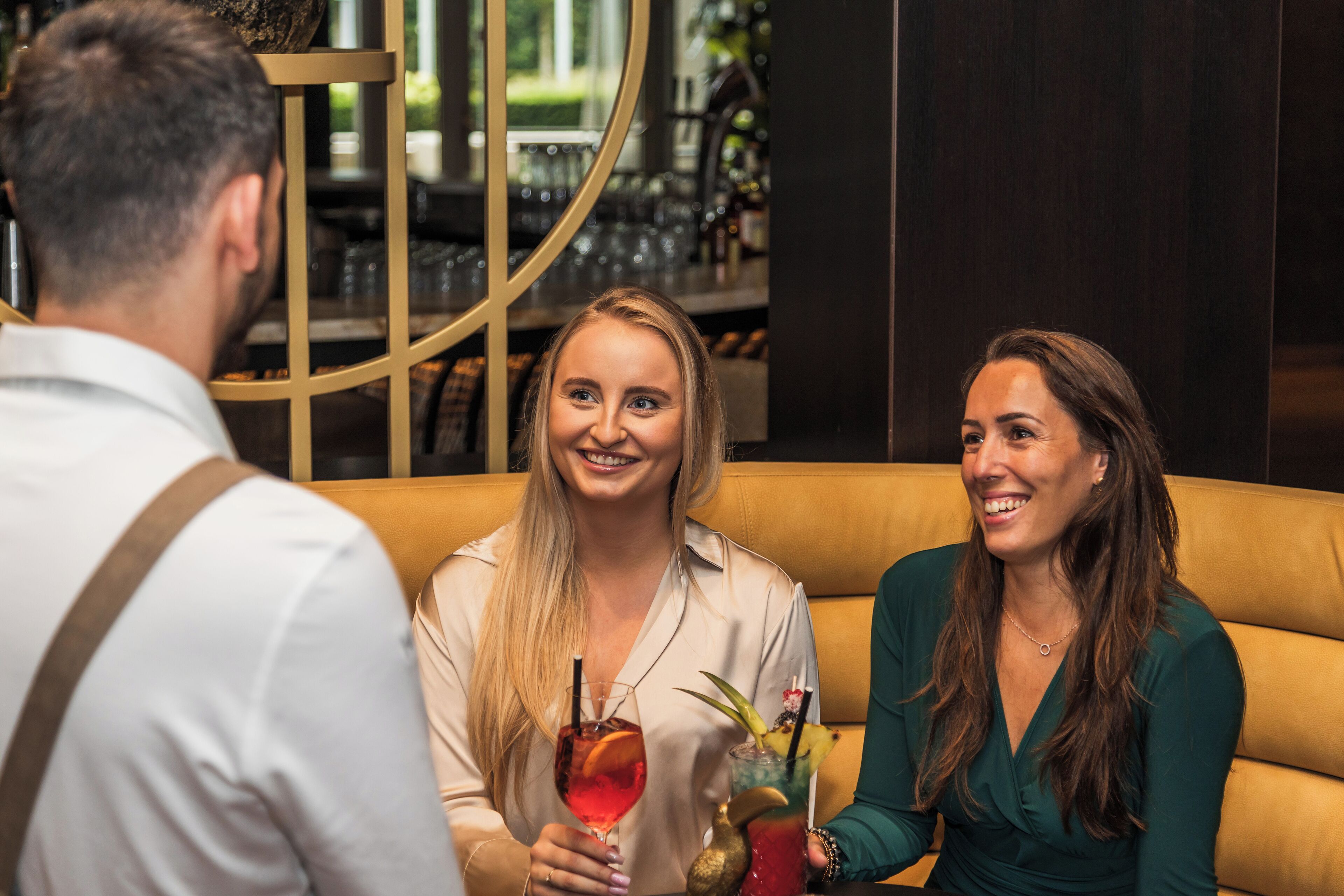 Eine Bar mit einer runden Bar, einer Couch und einer Person, die ein Getränk hält.