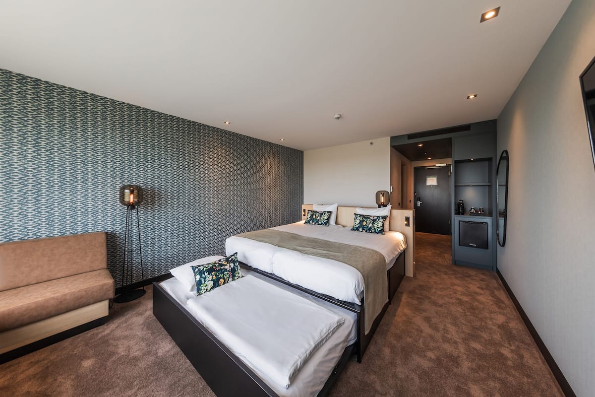Une chambre d’hôtel moderne avec un grand lit, un canapé et un petit espace bureau.