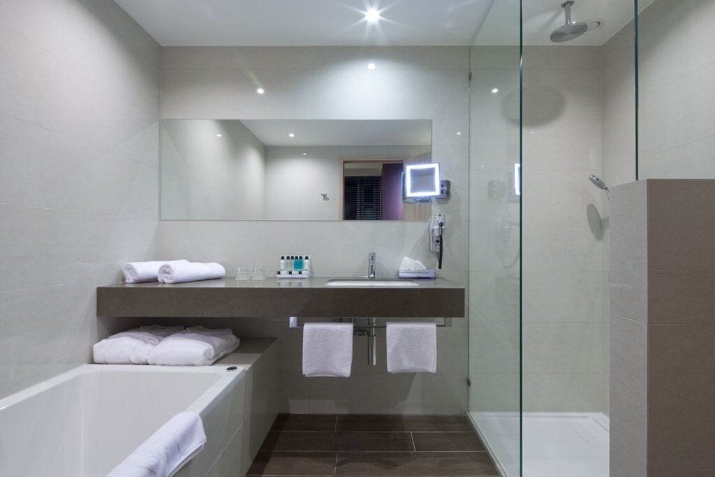 A modern bathroom with a glass-enclosed shower, a vanity with a mirror, and a bathtub.