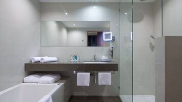 A modern bathroom with a glass-enclosed shower, a vanity with a mirror, and a bathtub.