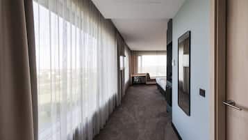 A hotel corridor with large windows, a desk, and a bed.