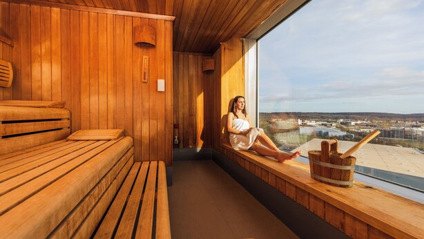 Una sauna con bancos de madera y un ventanal con vistas a la ciudad.