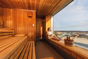 Una sauna con bancos de madera y un ventanal con vistas a la ciudad.