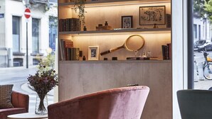 A modern interior with a bookshelf, a pink armchair, and a view of the street.