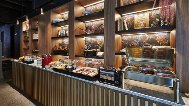 A buffet area with wooden shelves, various food items, and a glass display case.