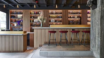 Un espace bar doté d’un comptoir en bois, de tabourets de bar rouges et d’une bibliothèque contenant divers objets.