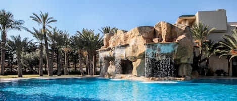 Una piscina cubierta, una piscina al aire libre, sombrillas