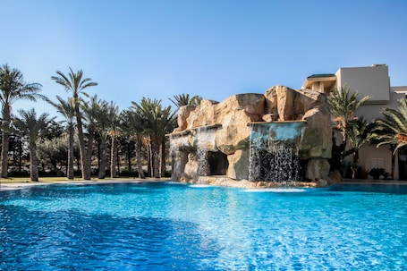 Una piscina techada, una piscina al aire libre, sombrillas
