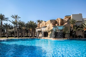 Una piscina cubierta, una piscina al aire libre, sombrillas