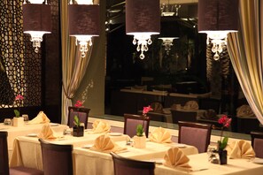 A restaurant with tables set for dining, featuring elegant table settings and hanging chandeliers. - The Russelior Hotel & Spa (Hammamet)