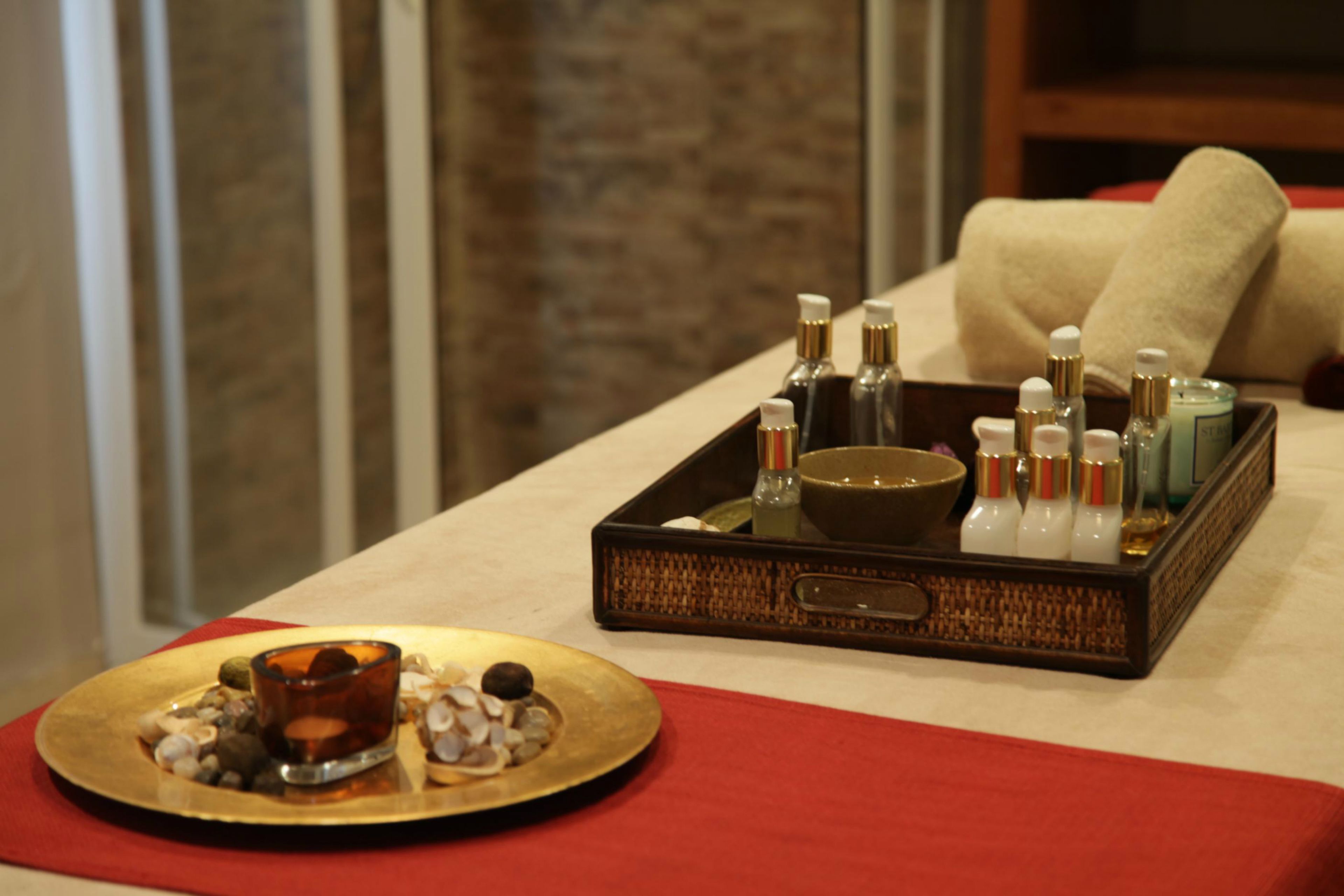 A tray with toiletries and a decorative plate with stones and a glass of amber liquid.