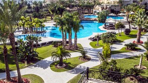 Un resort con una amplia piscina, palmeras y un césped bien cuidado.