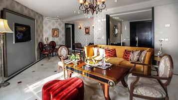 A spacious living room with a modern chandelier, a sofa set, and a dining area with a table set for two.