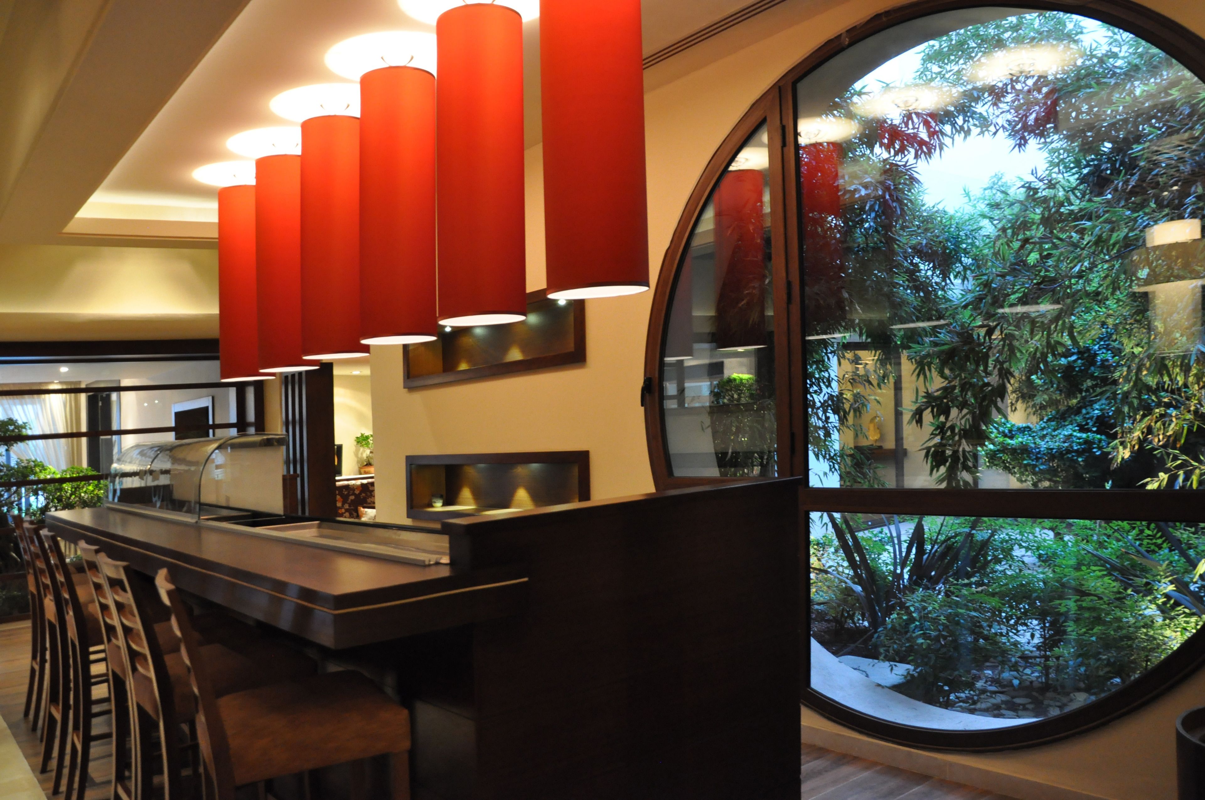A modern bar area with a large window offering a view of a lush garden.
