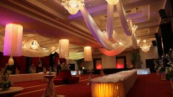 Un salón de banquetes con candelabros, telas decorativas y un escenario.