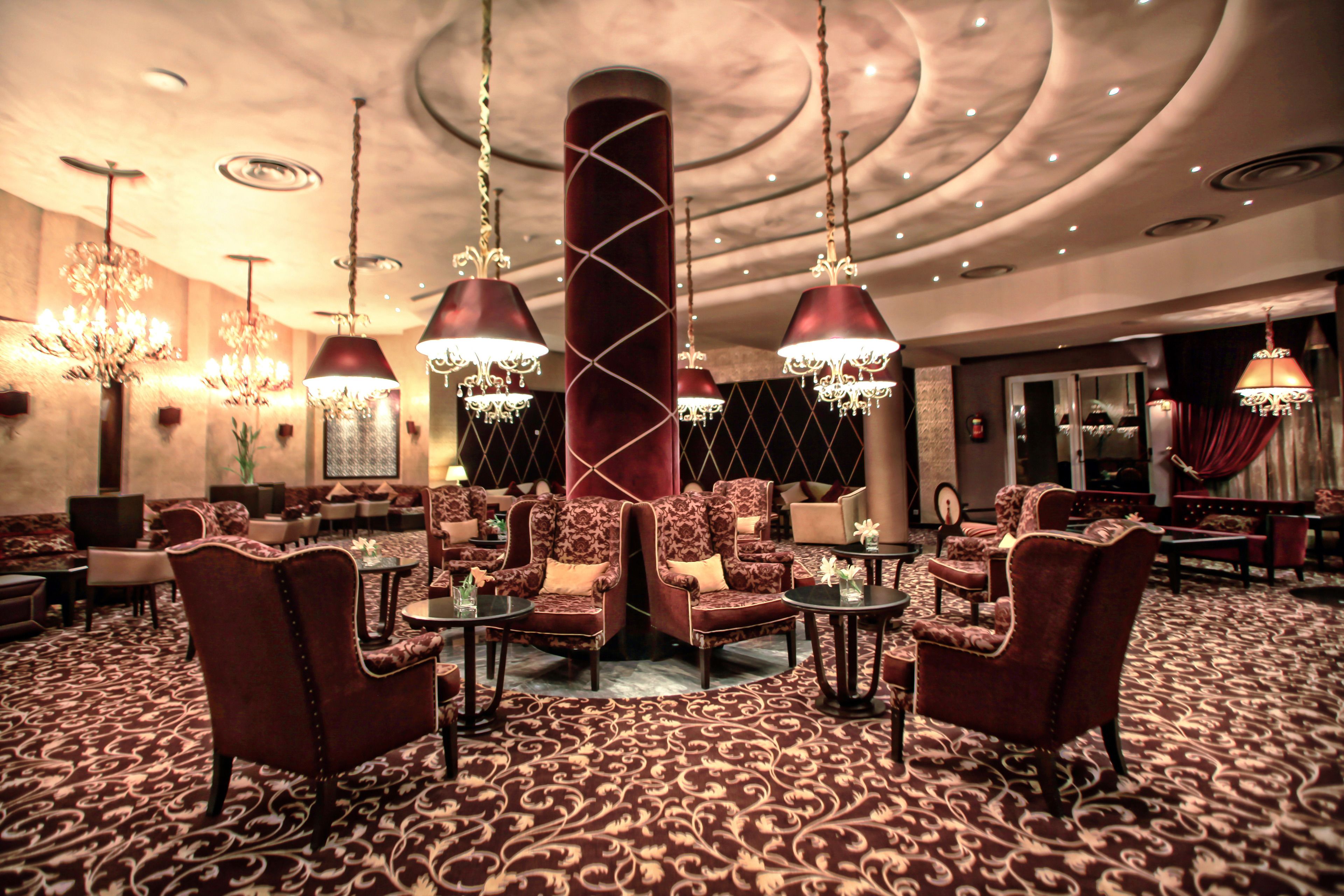 A luxurious lobby with ornate chandeliers, plush seating, and a patterned carpet.