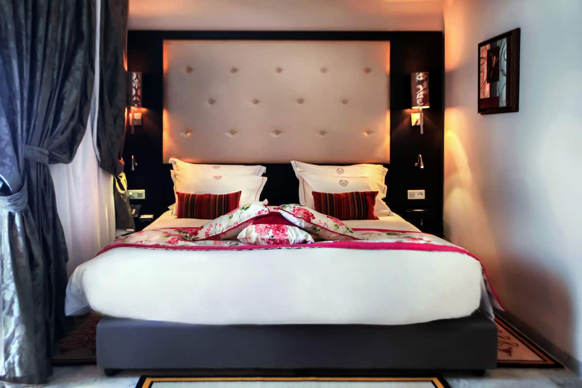 A large bed with a tufted headboard, two bedside tables, and a nightstand.