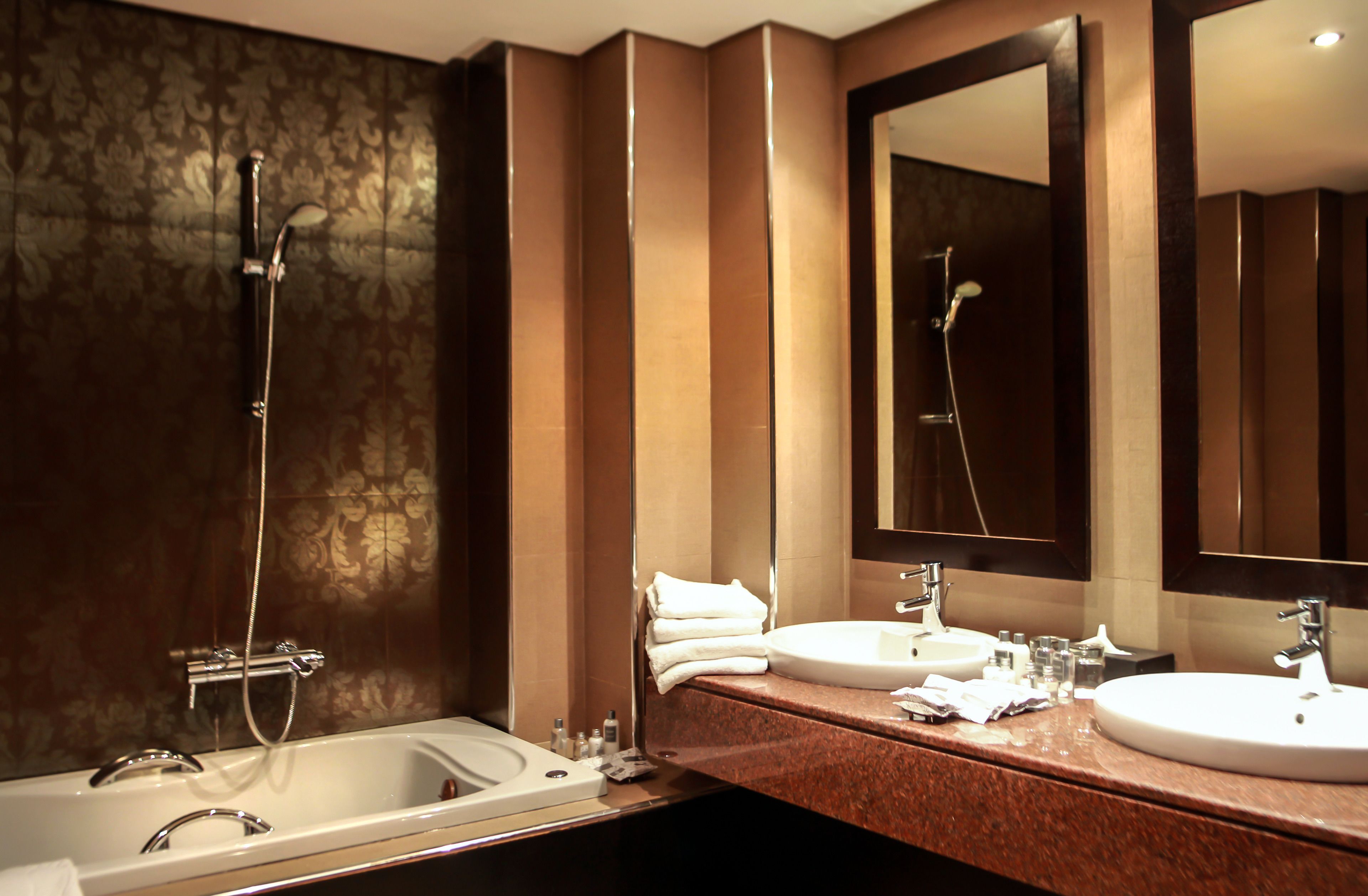 A modern bathroom with two sinks, a bathtub, and a large mirror.