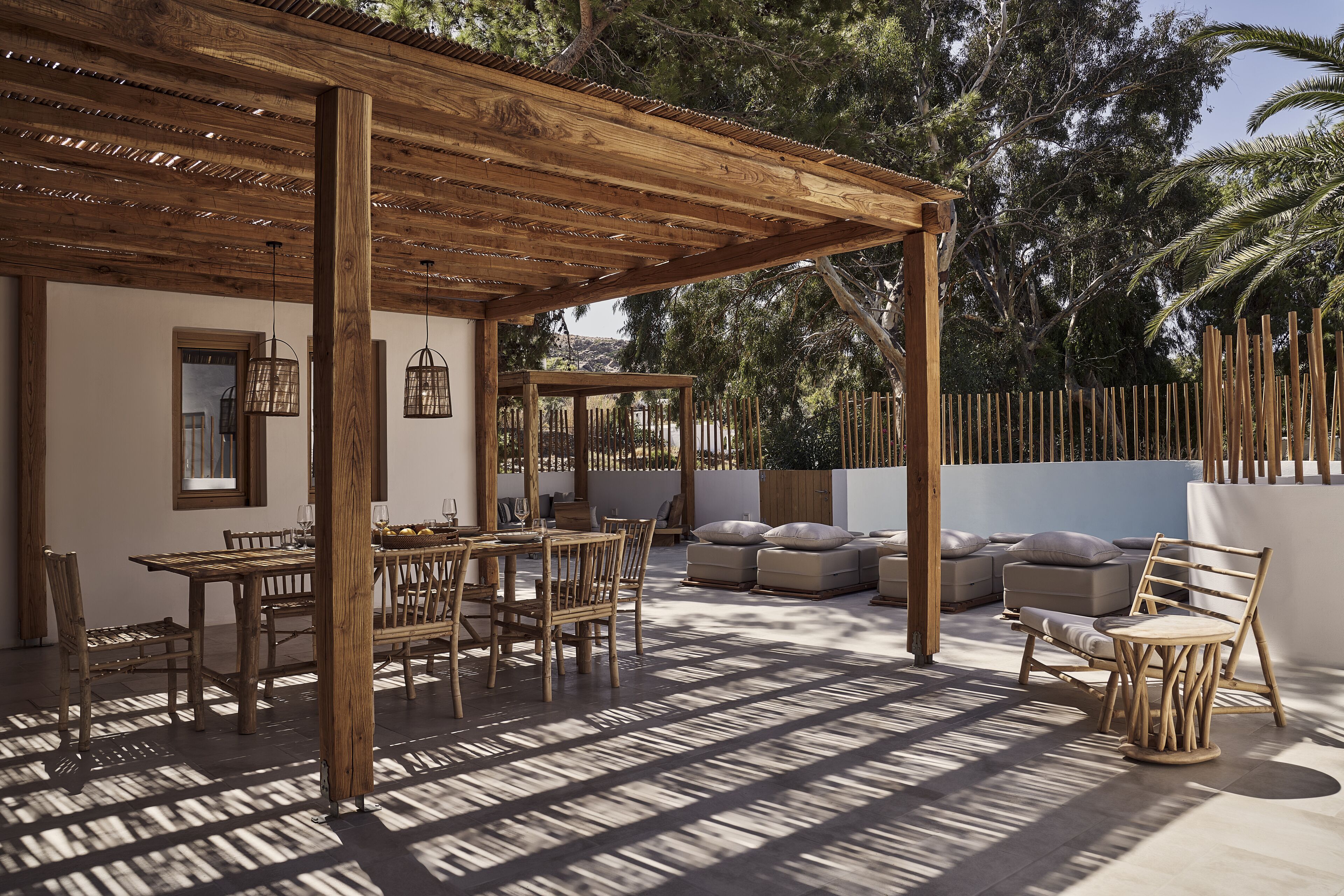 Eine Terrasse im Freien mit Holzmöbeln, einer Pergola und Blick auf Bäume.