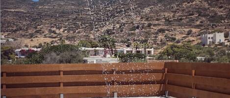 A rooftop pool with a water feature, lounge chairs, and a view of a mountainous landscape.