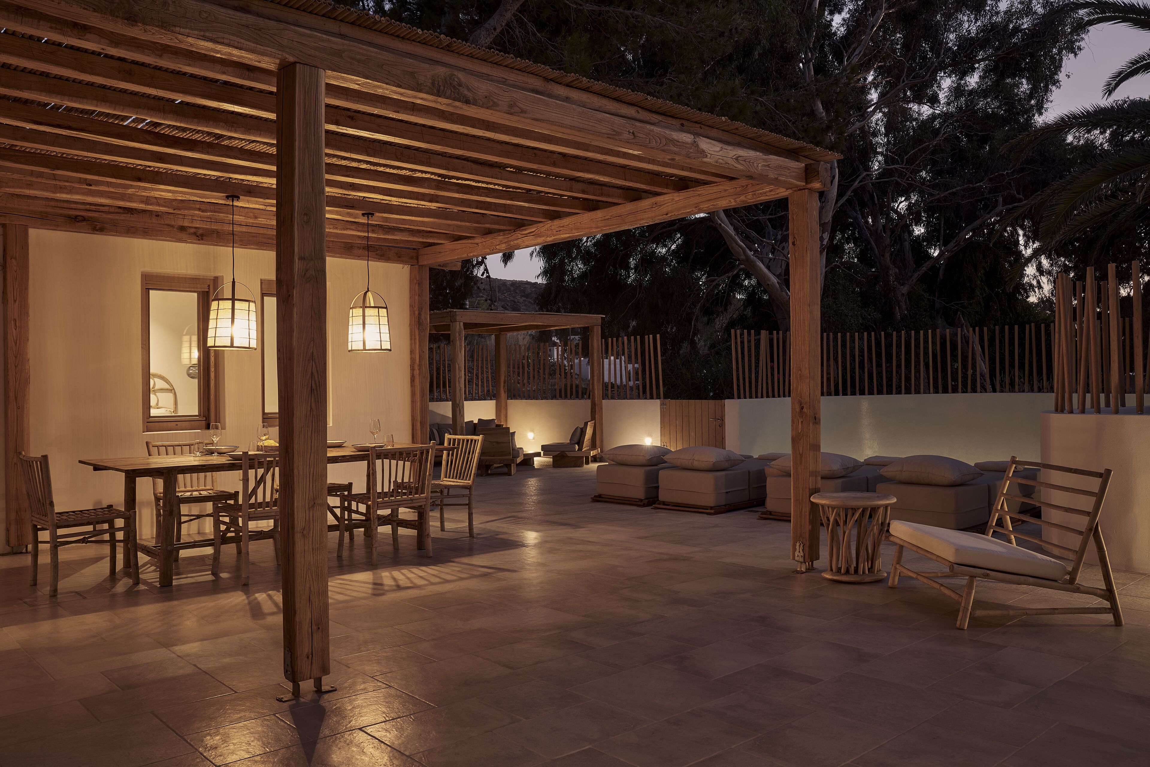 An outdoor patio area with wooden furniture, including a table and chairs, and a cushioned seating area.