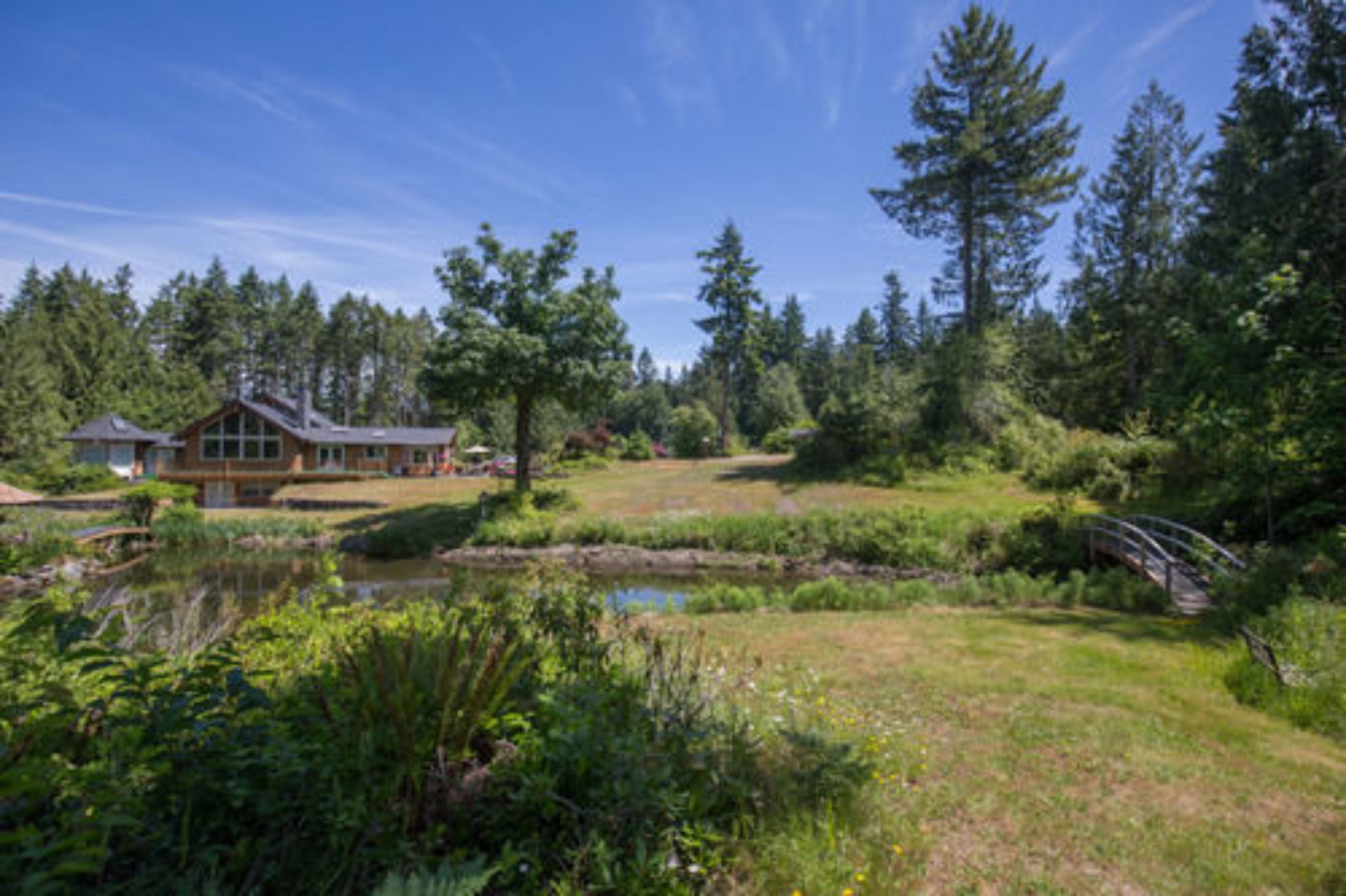 A lodge with a large wooden structure, surrounded by dense forest and a small pond.