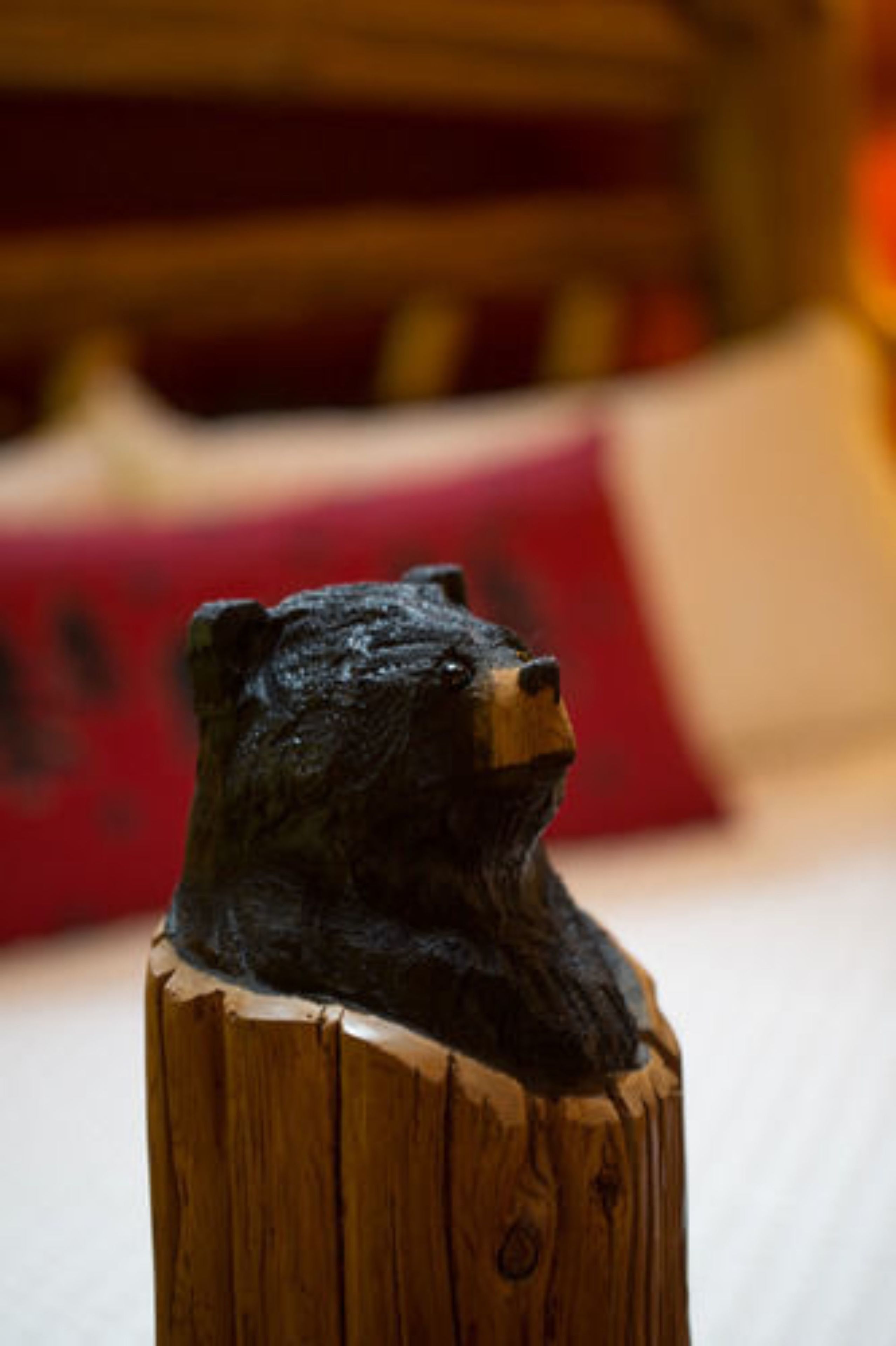A wooden sculpture of a bear's head on a wooden post.