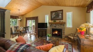 A cozy living room with a fireplace, leather sofa, and a dining area with wooden furniture. - A Hidden Haven & Water Garden Cottages (Port Angeles)