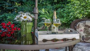 A round table with a bottle of champagne, two glasses, and a vase with flowers. - A Hidden Haven & Water Garden Cottages (Port Angeles)