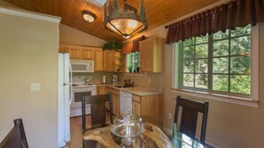 A kitchen with wooden cabinets, a microwave, and a dining table with chairs. - A Hidden Haven & Water Garden Cottages (Port Angeles)