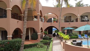 Un patio con piscina, sillas de descanso y una palmera.
